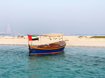 Sailboat moored on sea against clear sky