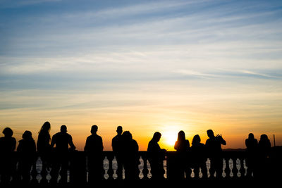 Silhouette of people enjoying the wonderful colorful sunset of farol da barra in salvador, bahia.