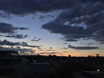 Silhouette houses against sky at sunset