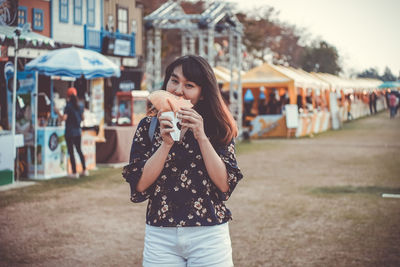 Portrait of woman eating food at market