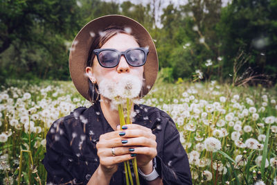 Young woman blowing dandelions at park