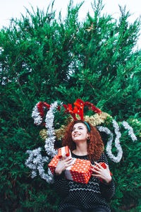 Smiling young women standing against tree