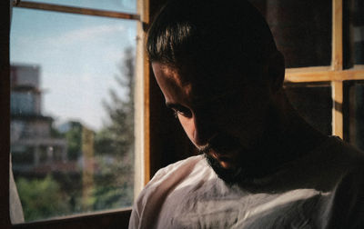 Portrait of young man looking through window