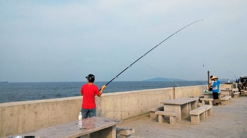 Rear view of man fishing in water