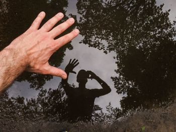 Cropped image of hand over reflection in puddle