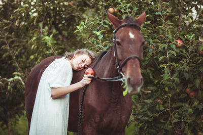 Woman leaning on horse in farm