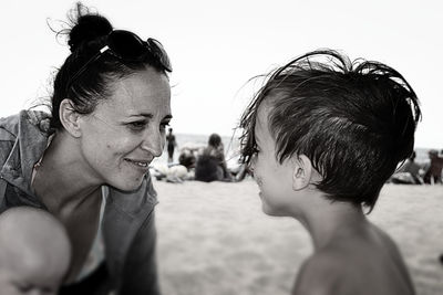 Smiling mother face to face with son at beach