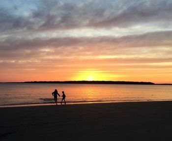 Silhouette of two children on beach at sunset