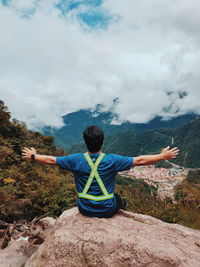 Rear view of man with arms outstretched against sky