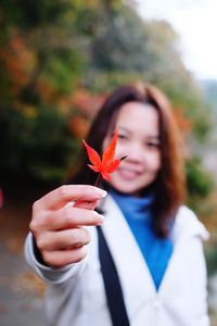 Close-up of young woman holding maple leaf