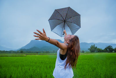 Rear view of woman with umbrella standing on field