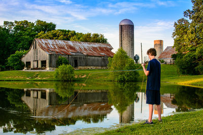 Reflection of woman standing on lake against built structures