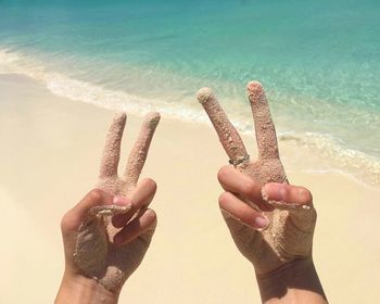 Close-up of hand holding sand at beach against sky