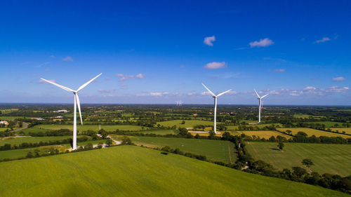 Windmills on field against sky