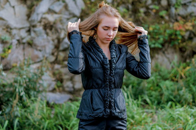 Young woman wearing black warm clothing against rock formation