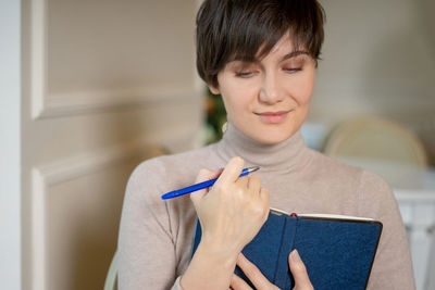 Beautiful woman looking at diary sitting at cafe