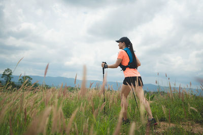 Rear view of woman standing on field against sky