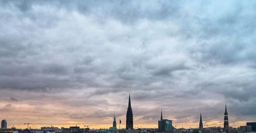 Buildings in city against cloudy sky