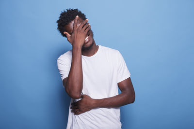 Side view of man standing against blue background