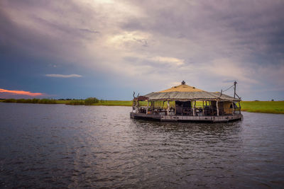 Stilt house on lake against sky