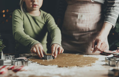 Mom and daughter make gingerbread cookies, cut out different shapes of cookies using cutting  mold