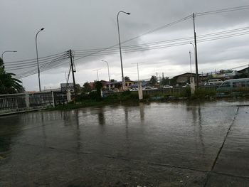 Wet river by city against sky