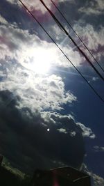 Low angle view of power lines against cloudy sky