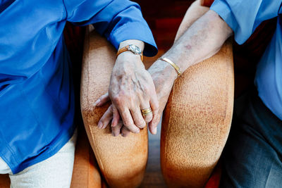 Elderly couple holding hands resting in armchair