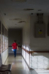 Rear view of man walking in corridor of building