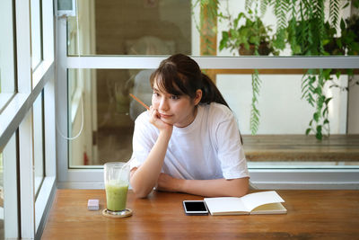 Young woman using phone while sitting on table