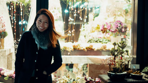 Portrait of smiling young woman standing against plants