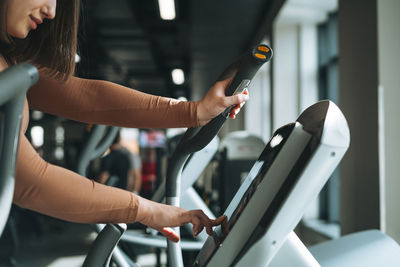 Young brunette woman training for cardio equipment at fitness club gym