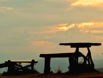 Silhouette bench on table against sky during sunset