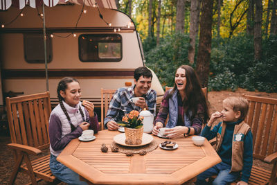 Happy family on camping trip relaxing in the autumn forest camper trailer. fall season outdoors trip