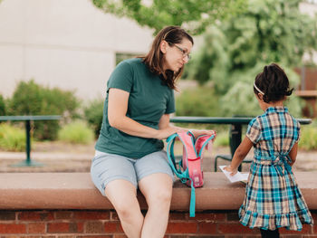 Young millennial mother sending daughter off back to school