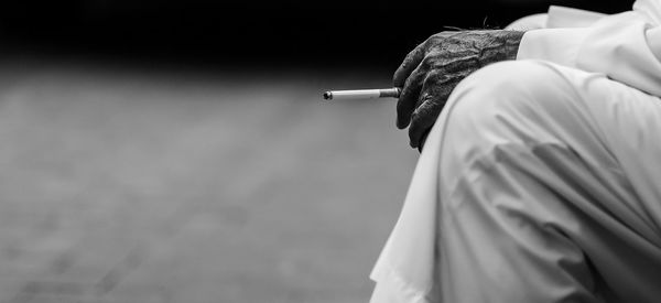 Midsection of man holding cigarette