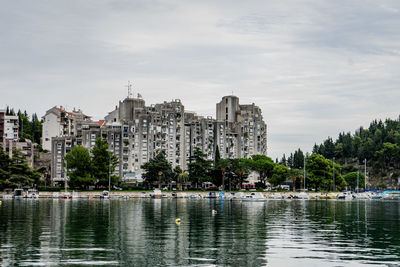 Buildings by lake against sky in city