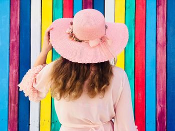 Rear view of woman wearing hat while standing by colorful wall