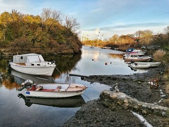 Boats moored on shore in city against sky