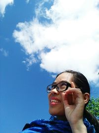 Low angle view of smiling young woman looking away against sky