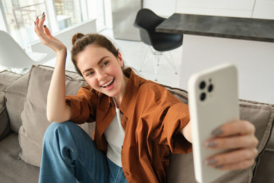 Portrait of boy using mobile phone while sitting on bed at home