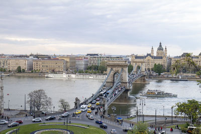 Bridge over river in city against cloudy sky