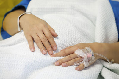 Close-up of woman holding hands on bed