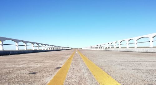 Surface level of road against clear blue sky