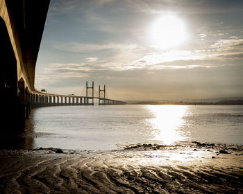 Bridge over sea against sky during sunset