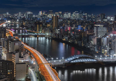 Aerial night view of the sumida river bridges and higways light-up with the skyscrapers of tokyo.