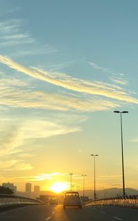 Cars on street against sky during sunset