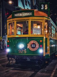 Train on illuminated street in city at night