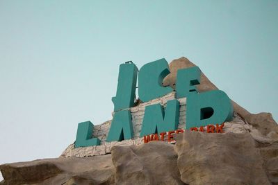 Low angle view of text on building against clear sky