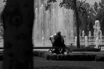 Rear view of woman sitting on tree stump